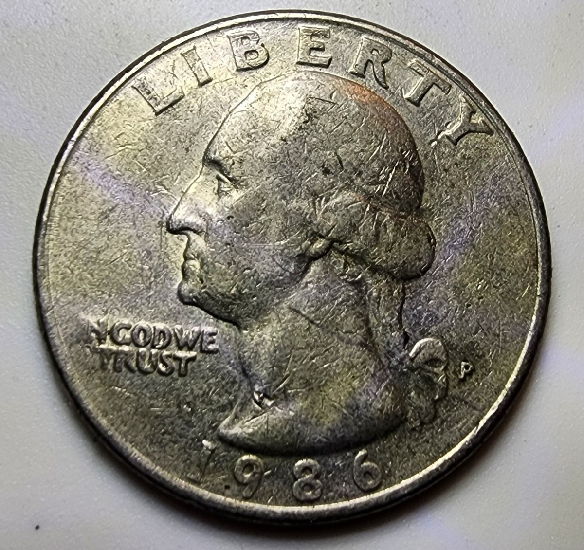 1986 quarter broadstrike error showing wider diameter flat rim and spread metal beyond normal collar